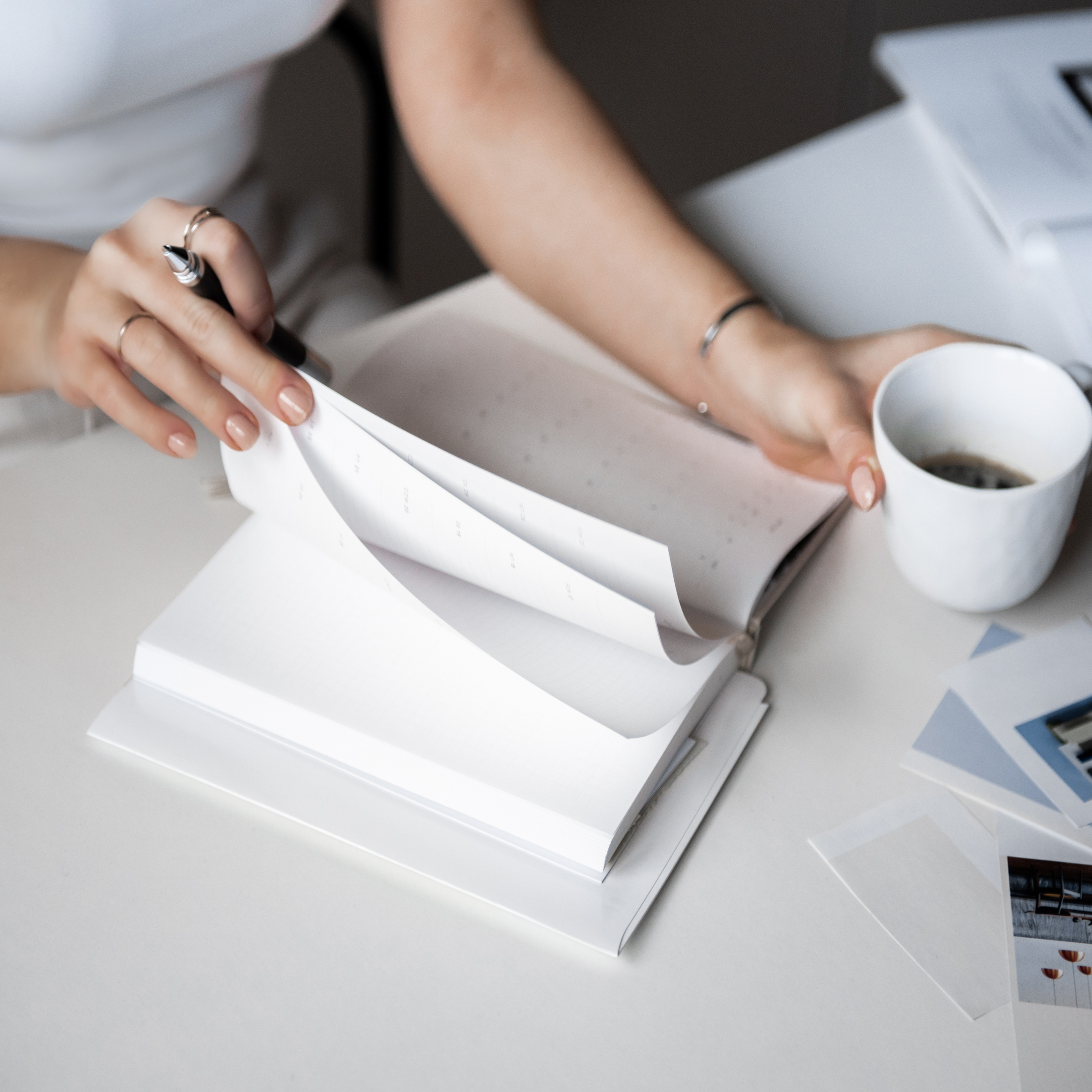 Woman flipping through a planner while holding a cup of coffee, symbolizing cycle tracking and mental health planning.